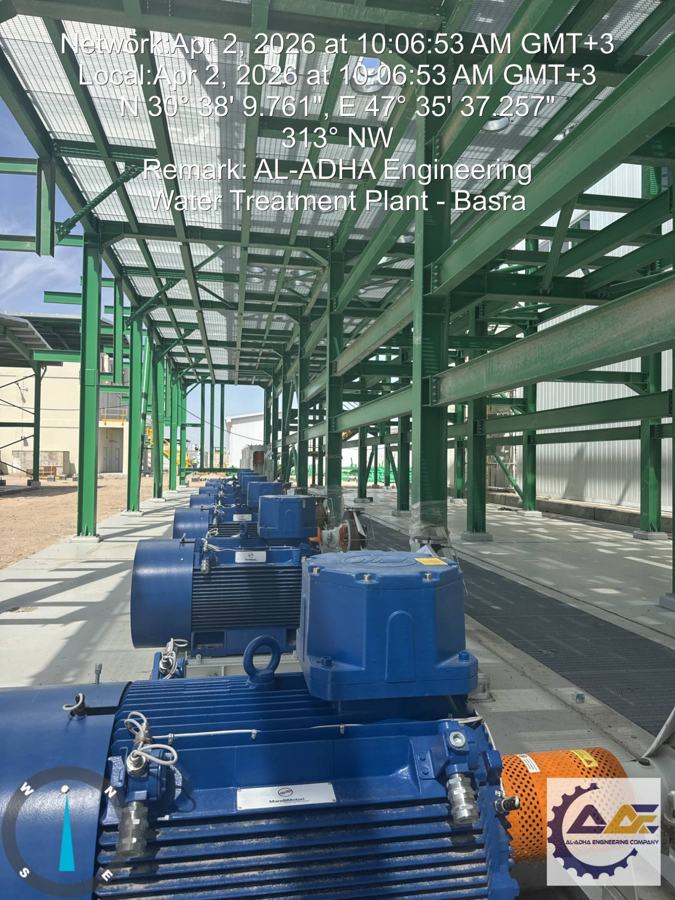 Row of blue motor-driven pumps beneath a green steel canopy at the Basra water treatment plant