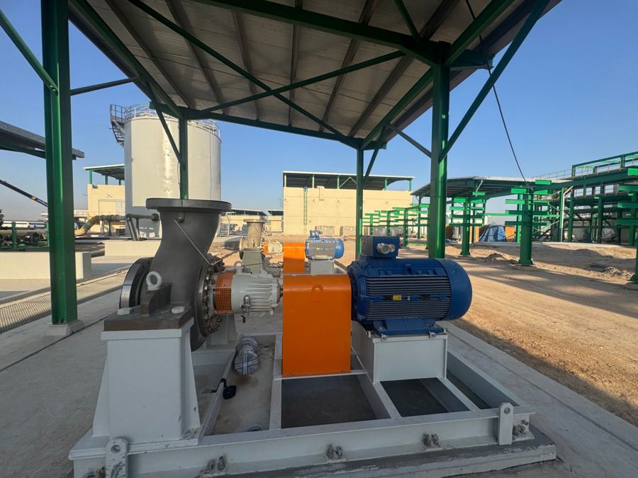 Pump skid with motor and piping installed under a steel-framed canopy